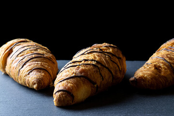 Croissant black background. Fresh pastry bread or french breakfast croissants with chocolate in bakery on black stone table. Homemade croissants, best for coffee.