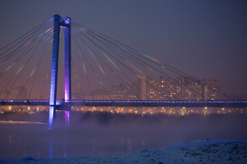 Obraz premium Bridge and fog across the river on the background of a beautiful sunset in winter