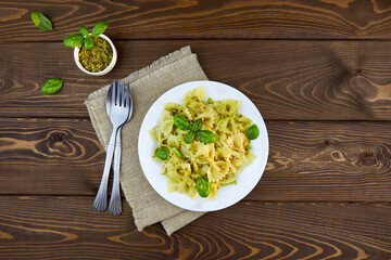 Farfalle pasta with pesto sauce on a wooden background