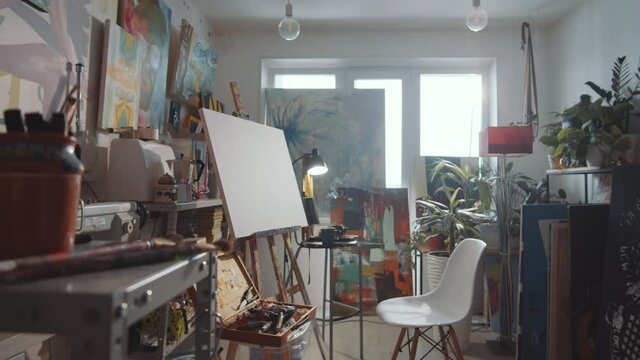 Zoom in shot of interior of creative studio of professional artist with paintings, canvas on easel, drawing tools and burning incense