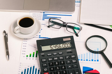 Work desk with calculator, coffee cup, glass magnifier and financial charts. An analyst, accountant...