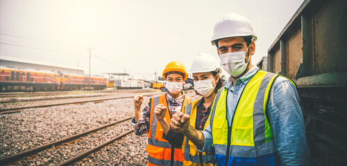 Caucasian man and asian woman of engineer team wearing a mask are standing in work site.