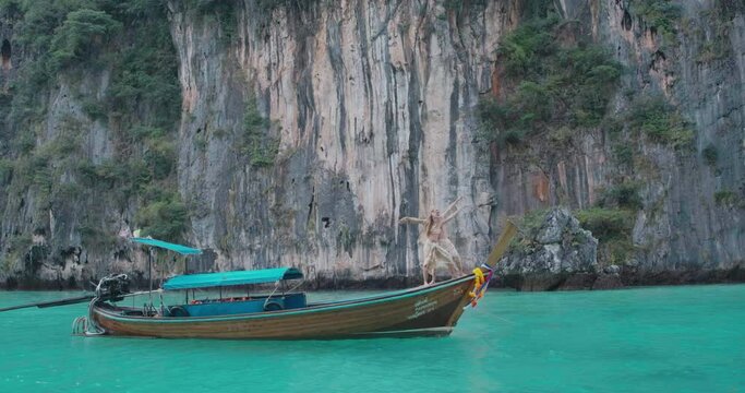 Aerial shot of sweet couple standing on long tail boat seeing beautiful seascape in summer vacation travel in Phi Phi Islands. Thai text translation on boat mean Boat's name, ID and Passenger Capacity