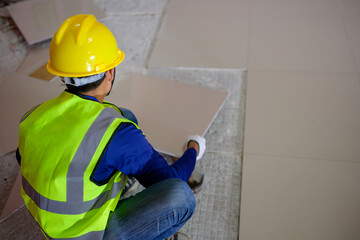 Construction workers work on broken tiles and old cement tiles as glue. Technicians are repairing new tiles.