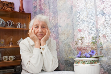 Elderly lonely woman depressed sitting at the table