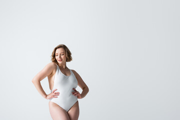 young overweight woman in swimwear posing with hands on hips isolated on white