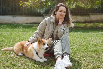 Ginger Welsh corgi Pembroke dog with his mistress in the garden playing and training together. Dog handler lesson. Veterinary hospital concept, love for animals. World's animal safety day