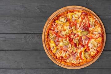 Top view of hot pizza on black wooden table
