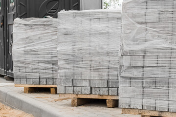 A pile of new paving slabs on a wooden pallet wrapped in plastic wrap. Building materials at the construction site