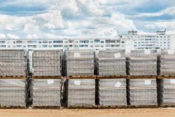 A pile of packed paving stone slabs industrial materials at a construction site against the background of old high-rise buildings