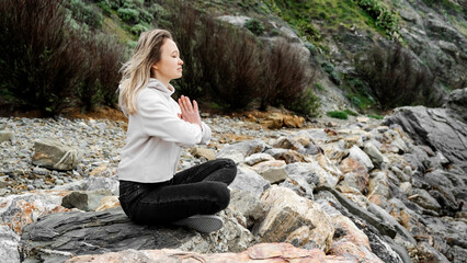 Blonde woman in lotus pose doing breathing pranayama exercise. Outdoor workout. Mindfulness zen spiritual meditation tips. Kundalini yoga. Reiki meditation. Relaxing. Unity with nature