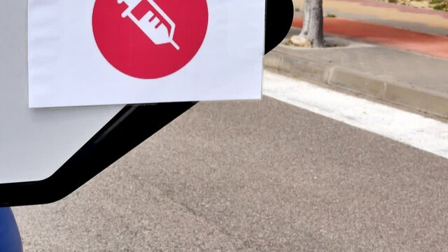 A needle sign pointing to a vaccination center. Tilt up.