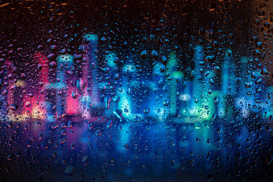 City view through a window on a rainy night,Rain drops on window with road light bokeh. Rainy days. Rain drops on window with street view ,rainy weather, rain background. © Inception
