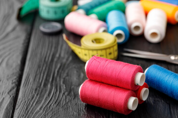 Colorful sewing utensils on black wooden surface