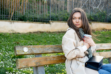 Naklejka premium Female in your twenties drinking from reusable coffee cup sitting in green park. Plastic free and eco friendly concept. Ecological lifestyle. Takeaway beverage. Zero waste