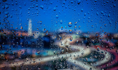 City view through a window on a rainy night,Rain drops on window with road light bokeh. Rainy days. Rain drops on window with street view ,rainy weather, rain background.