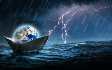 World in a paper boat floating in the ocean in a middle of a storm. Faith despite of world crisis and hardship conceptual theme. © funstarts33
