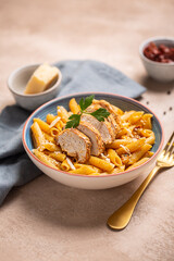 Pasta penne with cajun sauce and fried chicken on a table