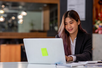 Portrait of Business young woman working on laptop computer doing finances,accounting analysis,report,data and pointing graph at the office.