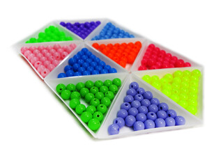 Photo background of round acrylic colored beads in ten white triangular packages on a white background