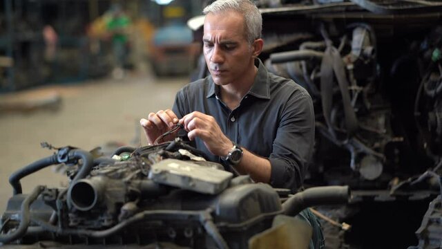 senior engineer checking old used car engine in machinery parts shop warehouse. old technician man Repair vehicle automobile machine in Recycle motor factory