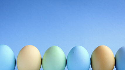 Easter holiday. Painted Easter eggs on a blue background. Pastel colors. Festive background with colorful eggs. Easter egg hunt game. Tradition.