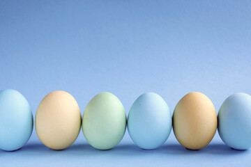 Easter holiday. Painted Easter eggs on a blue background. Pastel colors. Festive background with colorful eggs. Easter egg hunt game. Tradition.