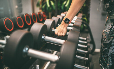 Fototapeta na wymiar Rows of dumbbells in the gym with hand.