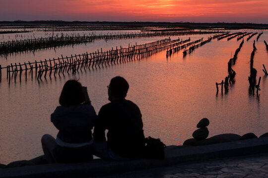 People watch the sunset in front of an oyster farm in Tainan