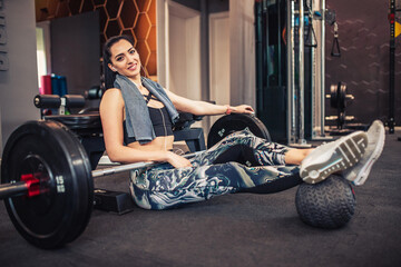 The woman is resting after training in the gym with a smile directed at the camera