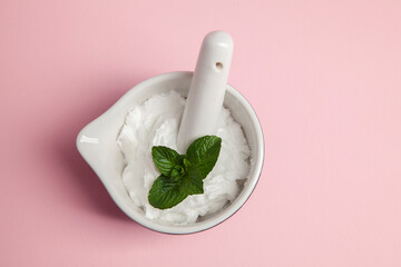 cosmetic cream in a bowl with pestle and aromatic herbs