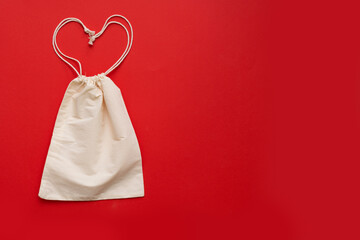 Reusable heart shaped shopping bag on red background. Cotton shopper on yellow background.Place for text