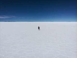 Isolated tourist enjoying endless infinite vastness dreamy landscape of white salt flat lake Salar...