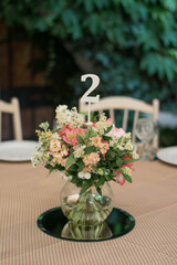 Centerpiece made of pink and white flowers stands in the middle of festive dinner table.