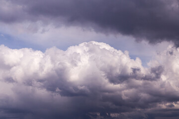 Obraz premium Storm sky. Dark grey, violet and white big cumulus rainy clouds on blue sky background, cloud texture, thunderstorm