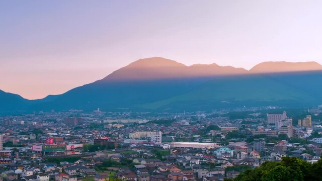 Beppu, Japan. A sunset time-lapse in a resort town of Beppu, Japan, with a view of mountains embracing the city and layers of the sun, panning video