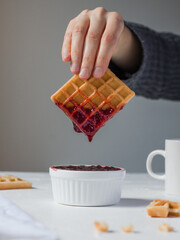 dipping waffles into red jam