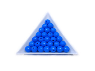 Photo background of round acrylic colored beads in white triangular packages on a white background