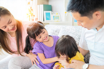 Happy Asian family playing together at sofa in home living room