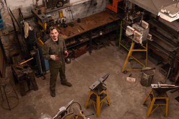 Traditional metalworking process in a forge. Blacksmith in the workshop posing, top view.