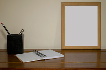 frame with white screen on table with notebook and pencil and pen holder