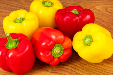 Red and yellow peppers on a brown wooden table