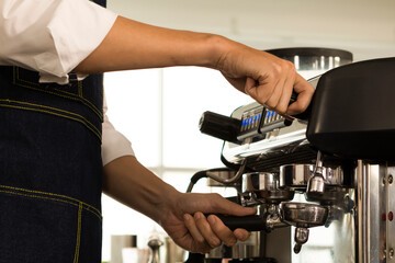 Young Barista preparing and making espresso with coffee machine. Barista preparing portafilter before making cappuccino in a coffee shop.