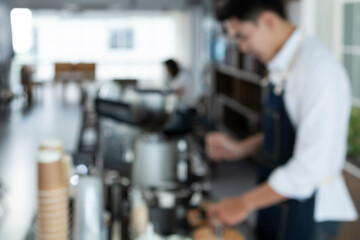 Blur photo of Young Barista preparing and making espresso with coffee machine. Barista making cappuccino in a coffee shop. Barista holding portafilter tamping and preparing cup of coffee.