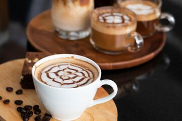 A cup of coffee with milk and scattered coffee beans on the wooden table. Coffee cup of Cappuccino on wooden table. Cup of hot latte art coffee on table.