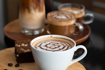 A cup of coffee with milk and scattered coffee beans on the wooden table. Coffee cup of Cappuccino on wooden table. Cup of hot latte art coffee on table.
