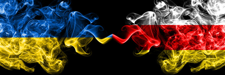 Ukraine, Ukrainian vs South Ossetia smoky mystic flags placed side by side. Thick colored silky abstract smokes flags.