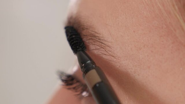 Make-up artist combs his eyebrows with a brush before coloring in a beauty salon