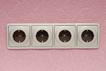 modern electric socket  in interior, grey wall outlet on pink wall,