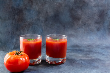 Tomato juice. Tomatoes in a basket and tomato juice in glasses. Copy space.